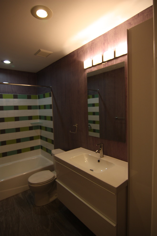 Design ideas for a medium sized modern family bathroom in Baltimore with a wall-mounted sink, flat-panel cabinets, white cabinets, an alcove bath, a shower/bath combination, a two-piece toilet, multi-coloured tiles, porcelain tiles, purple walls and porcelain flooring.