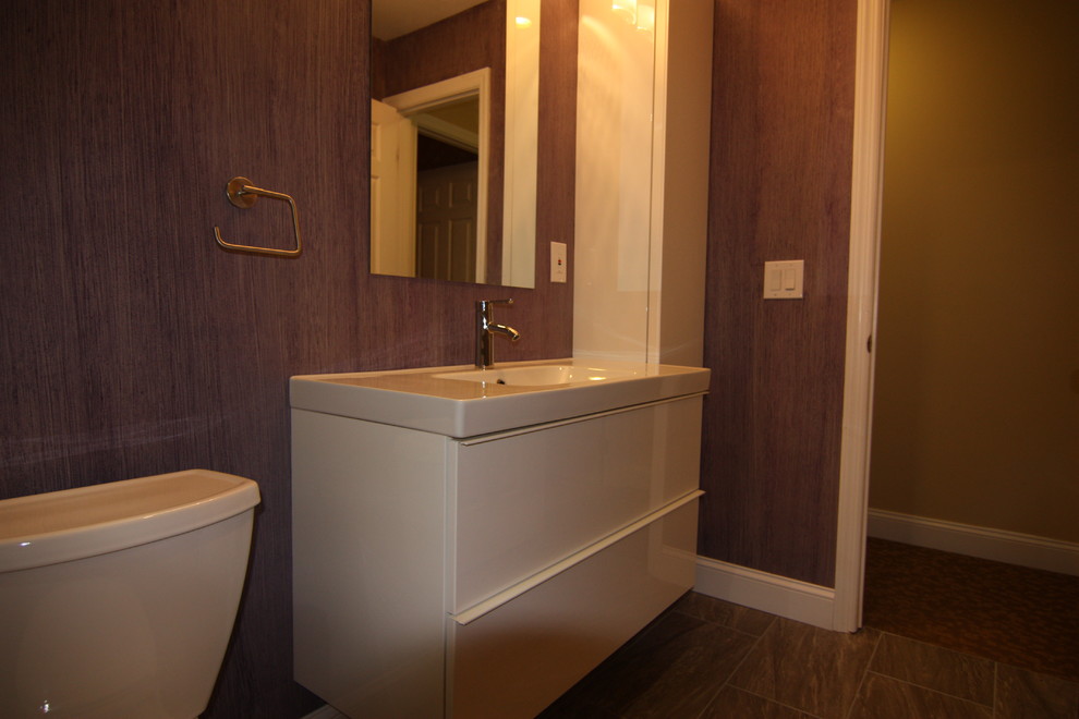 Modern inredning av ett mellanstort badrum för barn, med ett väggmonterat handfat, släta luckor, vita skåp, ett badkar i en alkov, en dusch/badkar-kombination, en toalettstol med separat cisternkåpa, flerfärgad kakel, porslinskakel, lila väggar och klinkergolv i porslin