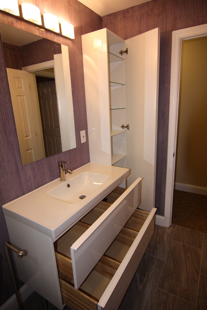 Photo of a medium sized modern family bathroom in Baltimore with a wall-mounted sink, flat-panel cabinets, white cabinets, an alcove bath, a shower/bath combination, a two-piece toilet, multi-coloured tiles, porcelain tiles, purple walls and porcelain flooring.