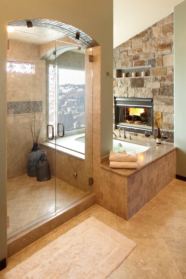 デンバーにある広いラスティックスタイルのおしゃれなマスターバスルーム (アンダーマウント型浴槽、ベージュのタイル、トラバーチンタイル、緑の壁、ラミネートの床、ベージュの床、開き戸のシャワー) の写真