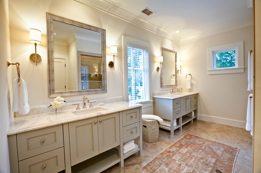 Klassisk inredning av ett badrum, med ett undermonterad handfat, möbel-liknande, grå skåp, marmorbänkskiva, en dubbeldusch, en toalettstol med separat cisternkåpa, grå kakel, stenkakel, grå väggar och kalkstensgolv