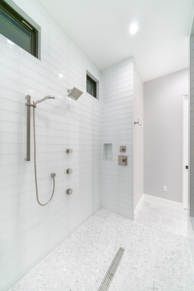 Foto på ett stort funkis grå en-suite badrum, med släta luckor, vita skåp, ett fristående badkar, en kantlös dusch, en toalettstol med hel cisternkåpa, grå kakel, marmorkakel, grå väggar, marmorgolv, ett nedsänkt handfat, marmorbänkskiva, grått golv och med dusch som är öppen