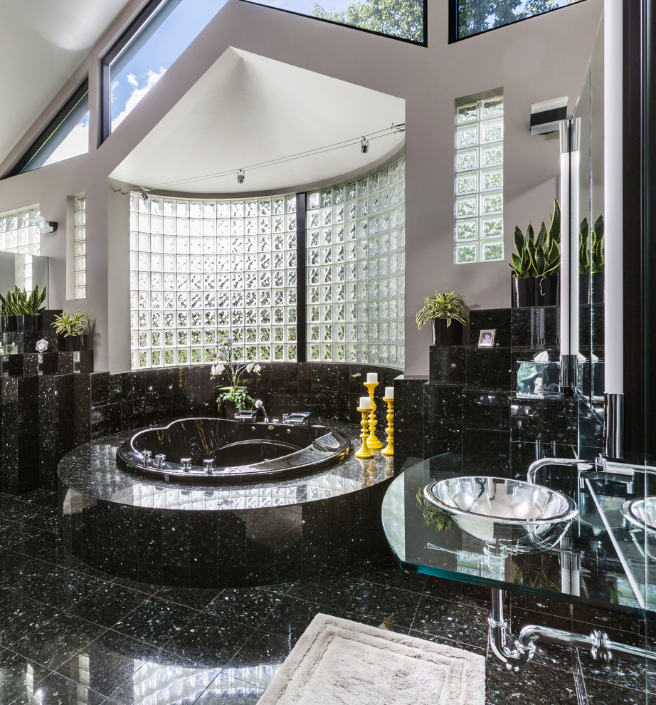 На фото: большая главная ванная комната в современном стиле с стеклянными фасадами, черными фасадами, гидромассажной ванной, двойным душем, унитазом-моноблоком, черной плиткой, каменной плиткой, бежевыми стенами, полом из керамической плитки, подвесной раковиной и стеклянной столешницей с