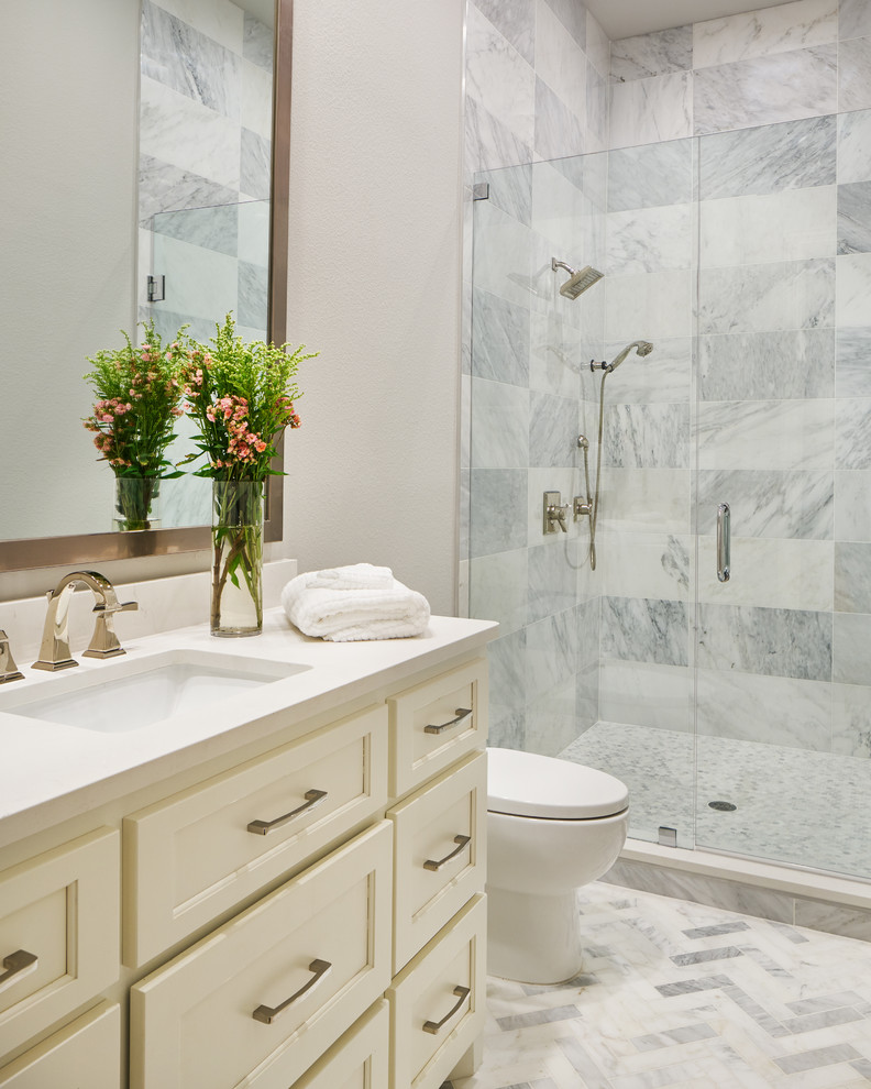 Mid-sized elegant white tile and stone tile white floor and ceramic tile bathroom photo in Other with recessed-panel cabinets, white cabinets, a one-piece toilet, gray walls, an undermount sink, quartz countertops and a hinged shower door