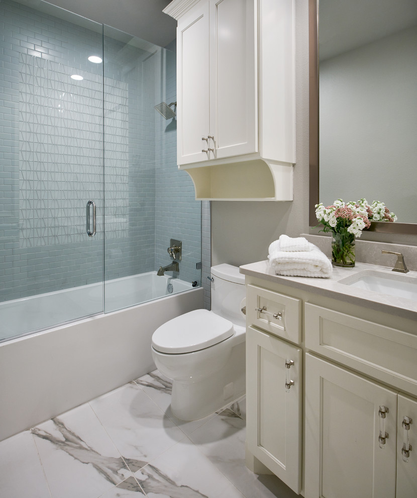 Mid-sized elegant white tile and stone tile porcelain tile and white floor tub/shower combo photo in Other with recessed-panel cabinets, white cabinets, a one-piece toilet, gray walls, quartz countertops and a hinged shower door