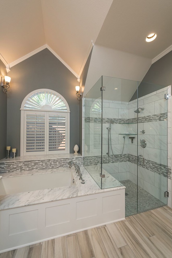 Large traditional ensuite bathroom in Dallas with shaker cabinets, white cabinets, a submerged bath, a built-in shower, grey tiles, marble tiles, grey walls, light hardwood flooring, a submerged sink, marble worktops, brown floors and a hinged door.
