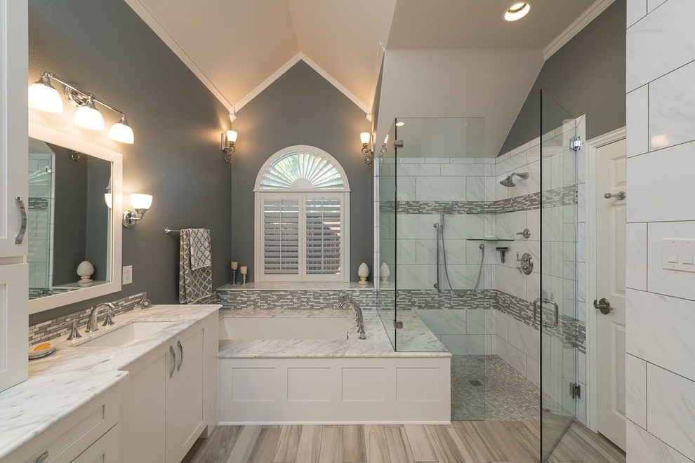 Idéer för stora vintage en-suite badrum, med skåp i shakerstil, vita skåp, ett undermonterat badkar, en kantlös dusch, grå kakel, marmorkakel, grå väggar, ljust trägolv, ett undermonterad handfat, marmorbänkskiva, brunt golv och dusch med gångjärnsdörr
