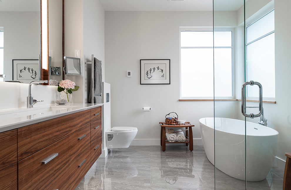 Großes Modernes Badezimmer mit flächenbündigen Schrankfronten, hellbraunen Holzschränken, freistehender Badewanne, Eckdusche, Wandtoilette und weißer Wandfarbe in Vancouver