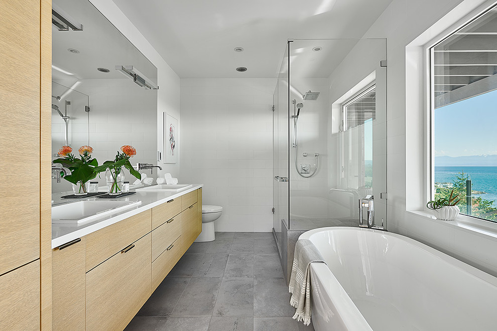 Example of a mid-sized minimalist master white tile and ceramic tile ceramic tile and gray floor bathroom design in Other with flat-panel cabinets, light wood cabinets, a one-piece toilet, white walls, a drop-in sink, quartz countertops, a hinged shower door and white countertops