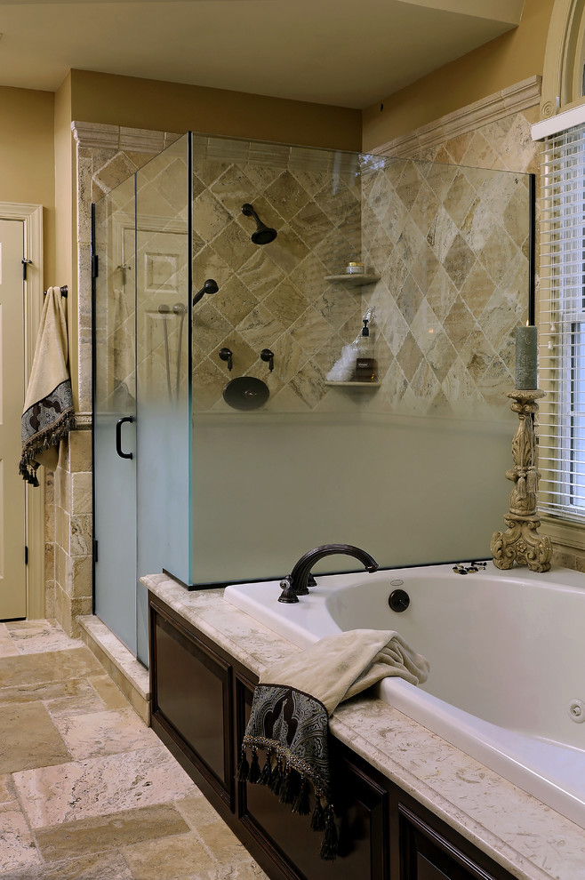 Cette photo montre une salle de bain chic en bois foncé avec un placard avec porte à panneau surélevé, une baignoire posée, une douche d'angle et un carrelage beige.