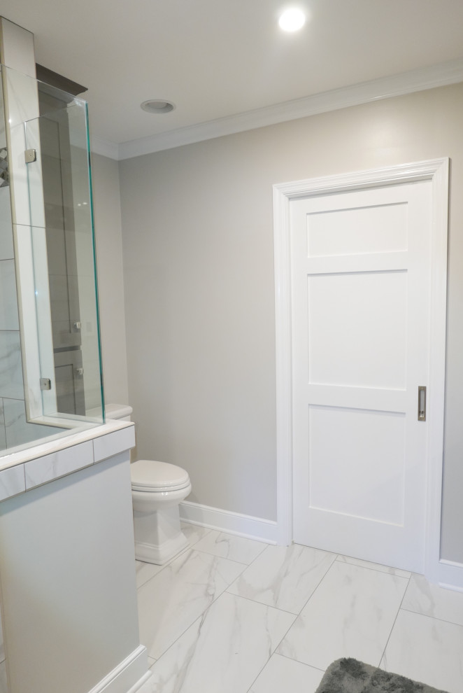 Cette photo montre une douche en alcôve principale chic de taille moyenne avec un placard à porte shaker, des portes de placard grises, WC séparés, un carrelage blanc, des carreaux de porcelaine, un mur gris, un sol en carrelage de porcelaine, un lavabo encastré, un plan de toilette en quartz modifié, un sol blanc, une cabine de douche à porte battante et un plan de toilette multicolore.