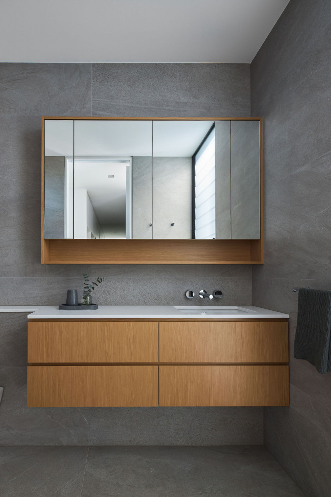 Стильный дизайн: ванная комната в современном стиле с плоскими фасадами, светлыми деревянными фасадами, серой плиткой, серыми стенами, врезной раковиной, серым полом, белой столешницей, тумбой под одну раковину и подвесной тумбой - последний тренд
