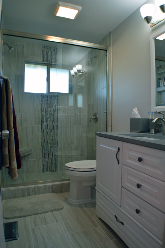 Kleines Klassisches Duschbad mit profilierten Schrankfronten, weißen Schränken, Duschnische, Wandtoilette mit Spülkasten, Porzellanfliesen, Unterbauwaschbecken, Vinylboden und Mineralwerkstoff-Waschtisch in Seattle
