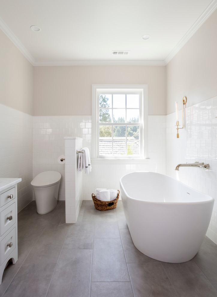 Large traditional ensuite wet room bathroom in Portland with shaker cabinets, white cabinets, a freestanding bath, a one-piece toilet, white tiles, ceramic tiles, beige walls, ceramic flooring, a submerged sink, marble worktops, grey floors, a hinged door and multi-coloured worktops.