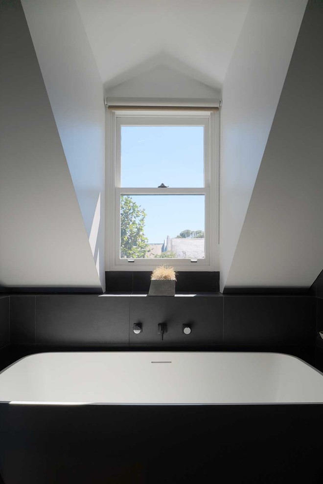 На фото: маленькая главная ванная комната в современном стиле с плоскими фасадами, светлыми деревянными фасадами, отдельно стоящей ванной, открытым душем, черной плиткой, керамической плиткой, белыми стенами, полом из керамической плитки, врезной раковиной, мраморной столешницей, черным полом и открытым душем для на участке и в саду