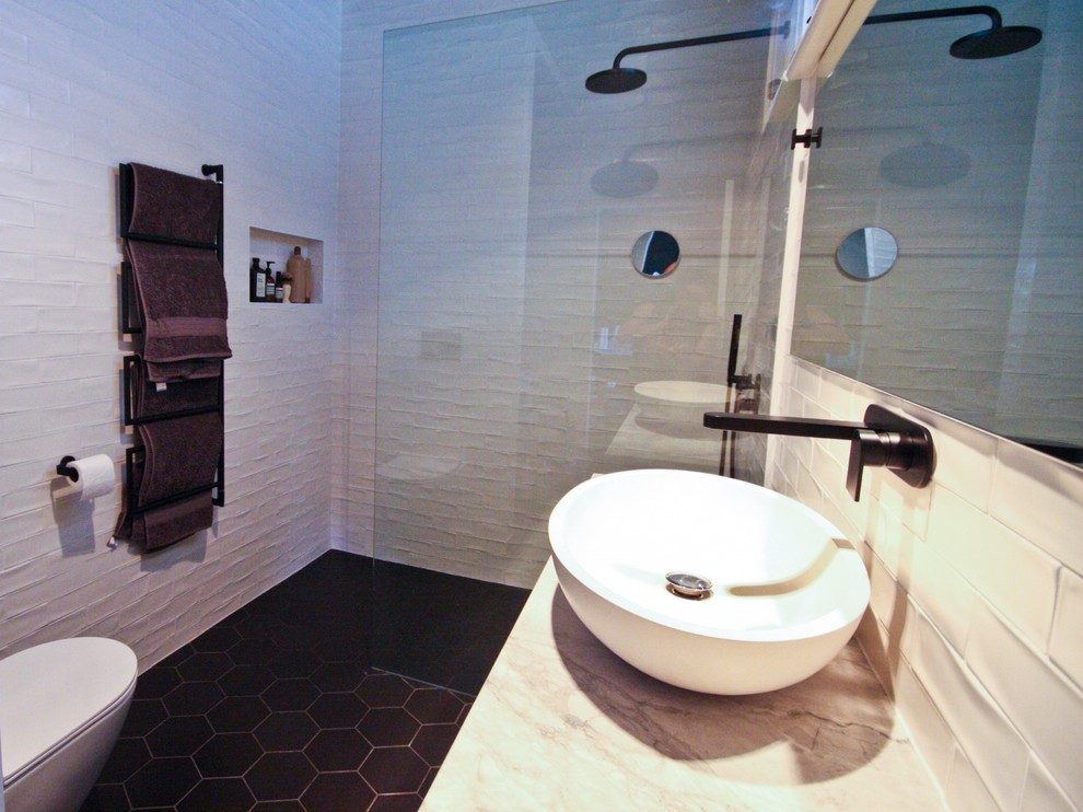 メルボルンにある高級な中くらいなモダンスタイルのおしゃれなマスターバスルーム (フラットパネル扉のキャビネット、黒いキャビネット、オープン型シャワー、壁掛け式トイレ、白いタイル、セラミックタイル、白い壁、コルクフローリング、ベッセル式洗面器、大理石の洗面台、黒い床、オープンシャワー、白い洗面カウンター) の写真