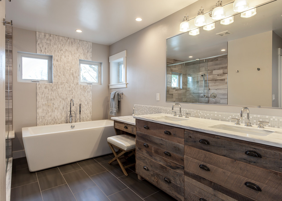 Réalisation d'une très grande salle de bain principale design en bois vieilli avec un placard à porte plane, une baignoire indépendante, une douche ouverte, un carrelage beige, des carreaux de céramique, un mur gris, un lavabo encastré et un plan de toilette en granite.
