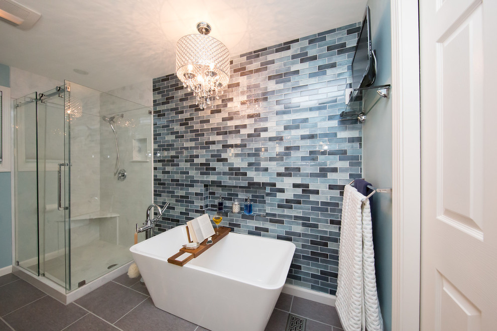 На фото: главная ванная комната среднего размера в стиле модернизм с фасадами с выступающей филенкой, серыми фасадами, отдельно стоящей ванной, угловым душем, биде, синей плиткой, плиткой из листового стекла, синими стенами, монолитной раковиной, мраморной столешницей, серым полом и душем с раздвижными дверями