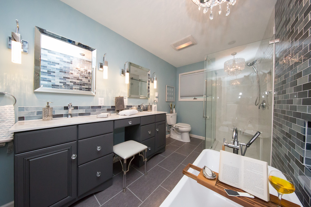 Exemple d'une salle de bain principale moderne de taille moyenne avec un placard avec porte à panneau surélevé, des portes de placard grises, une baignoire indépendante, une douche d'angle, un bidet, un carrelage bleu, des plaques de verre, un mur bleu, un lavabo intégré, un plan de toilette en marbre, un sol gris et une cabine de douche à porte coulissante.