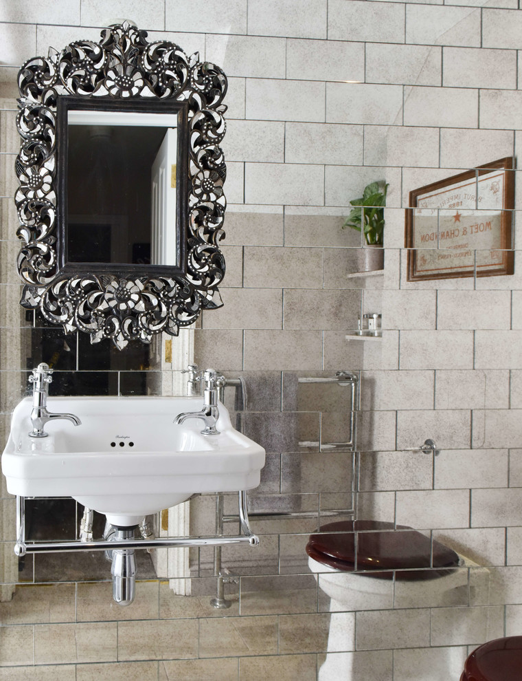 Idée de décoration pour une salle de bain bohème avec des carreaux de miroir et un lavabo suspendu.
