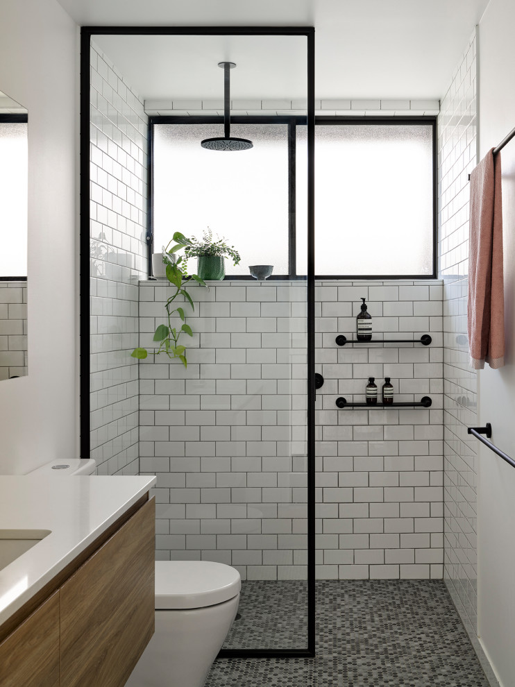 На фото: ванная комната в современном стиле с плоскими фасадами, фасадами цвета дерева среднего тона, белой плиткой, белыми стенами, полом из мозаичной плитки, врезной раковиной, серым полом, белой столешницей и подвесной тумбой