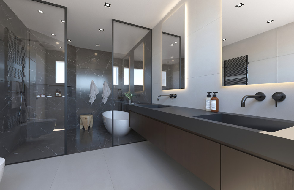 Idéer för att renovera ett stort funkis svart svart en-suite badrum, med släta luckor, bruna skåp, ett fristående badkar, en kantlös dusch, en vägghängd toalettstol, grå kakel, porslinskakel, grå väggar, klinkergolv i porslin, ett undermonterad handfat, bänkskiva i akrylsten, grått golv och med dusch som är öppen