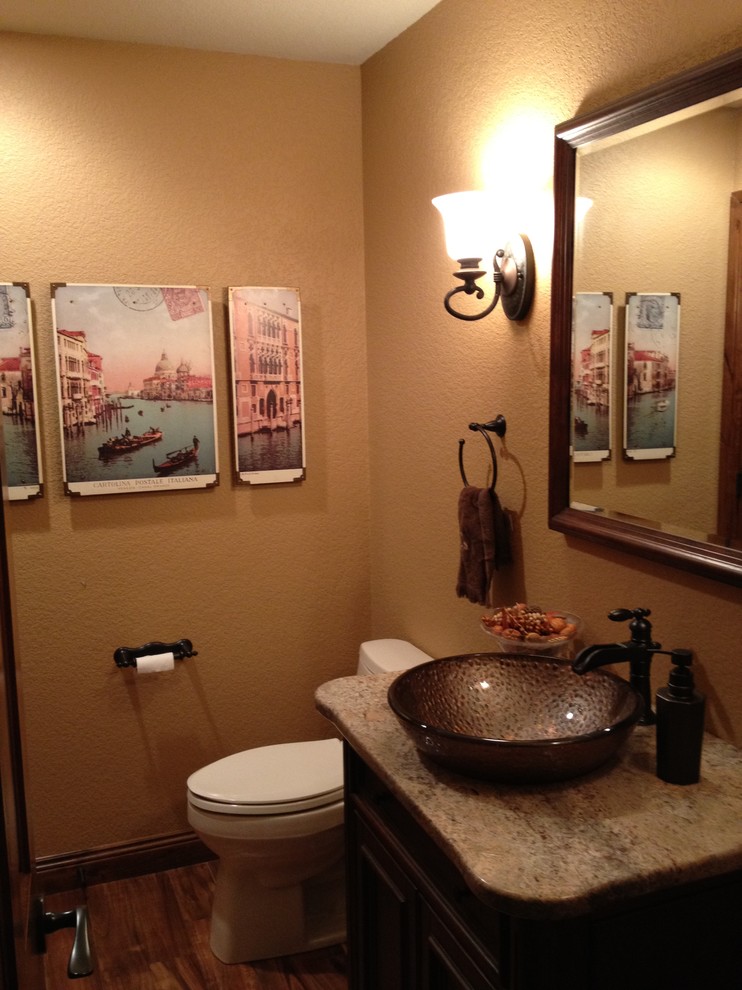 Foto på ett litet amerikanskt badrum med dusch, med luckor med upphöjd panel, skåp i mörkt trä, en toalettstol med separat cisternkåpa, beige väggar, mellanmörkt trägolv, ett fristående handfat och granitbänkskiva