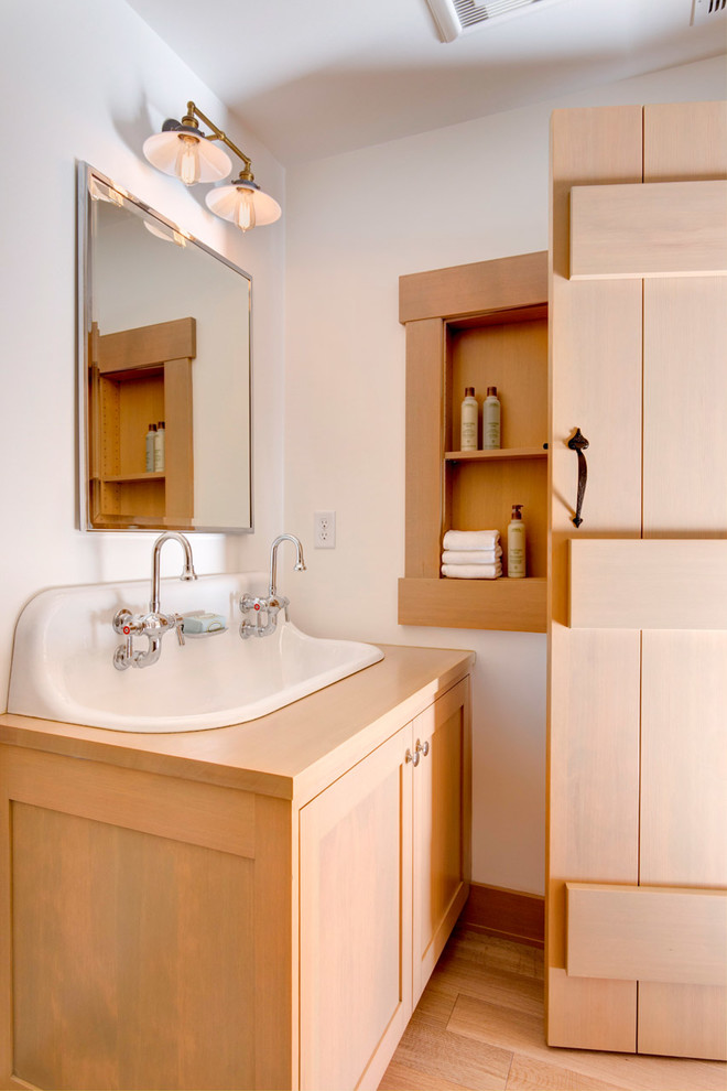 Example of a transitional medium tone wood floor and brown floor bathroom design in Portland with shaker cabinets, brown cabinets, white walls, a trough sink, wood countertops and brown countertops