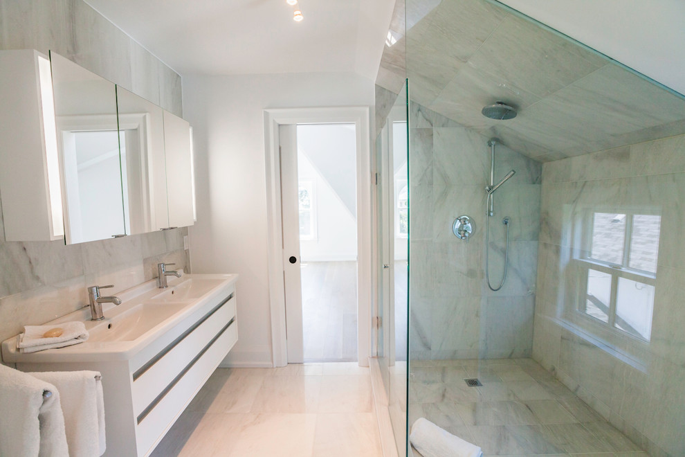 Inspiration for a medium sized modern ensuite bathroom in Toronto with an integrated sink, flat-panel cabinets, white cabinets, a corner shower, white tiles, stone tiles, white walls, marble flooring and a two-piece toilet.