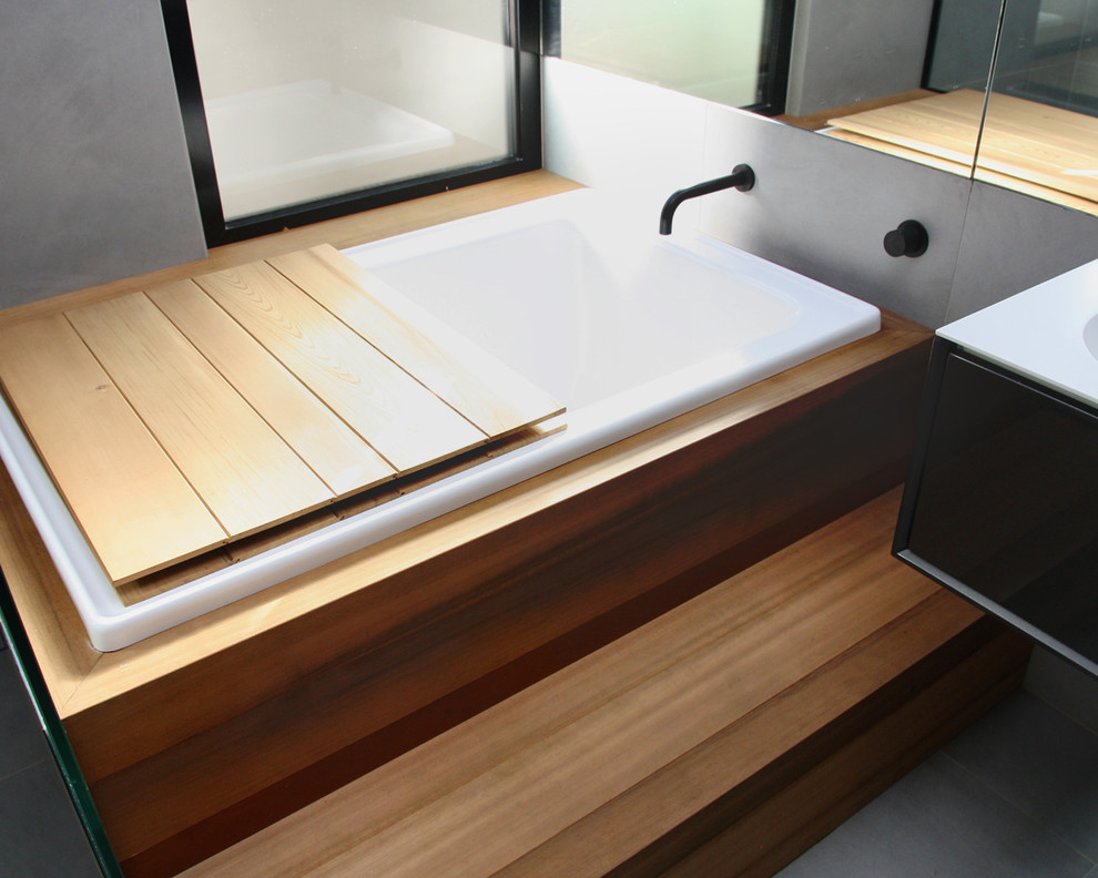 Inspiration pour une grande salle d'eau design en bois brun avec un placard en trompe-l'oeil, un bain japonais, une douche ouverte, WC à poser, un carrelage gris, des carreaux de béton, un mur gris, carreaux de ciment au sol, une vasque, un plan de toilette en bois, un sol gris et une cabine de douche à porte battante.