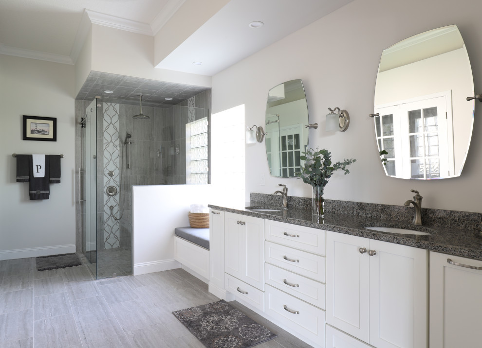 This is an example of a medium sized contemporary ensuite bathroom in Jacksonville with shaker cabinets, white cabinets, a walk-in shower, a two-piece toilet, grey tiles, porcelain tiles, grey walls, porcelain flooring, a submerged sink, granite worktops, grey floors, a sliding door, grey worktops, a wall niche, double sinks and a built in vanity unit.