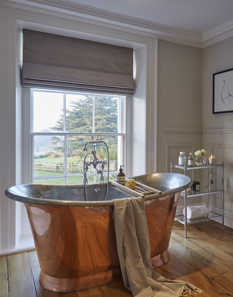 Exempel på ett klassiskt badrum, med ett fristående badkar, grå väggar och mellanmörkt trägolv