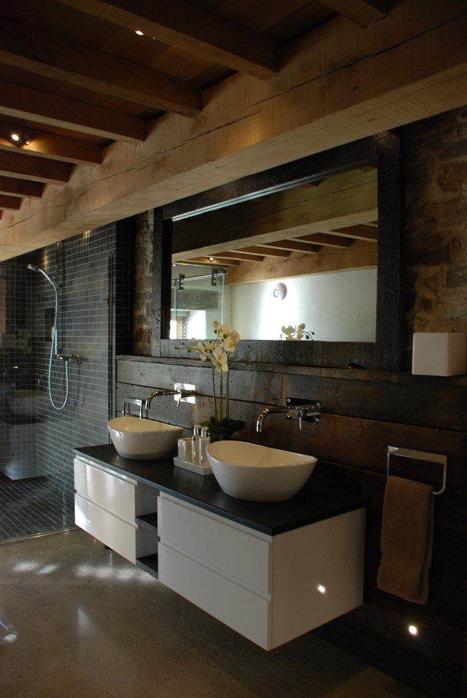Bathroom - large rustic master concrete floor, brown floor, double-sink and exposed beam bathroom idea in Cornwall with flat-panel cabinets, white cabinets, granite countertops, a wall-mount toilet, brown walls, a vessel sink, a hinged shower door, gray countertops and a floating vanity