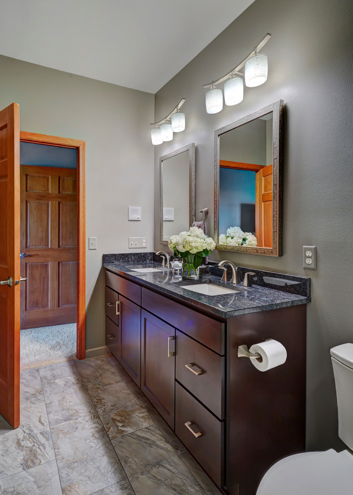 This is an example of a medium sized classic ensuite bathroom in Milwaukee with shaker cabinets, dark wood cabinets, an alcove shower, a two-piece toilet, grey tiles, porcelain tiles, porcelain flooring, a submerged sink and granite worktops.