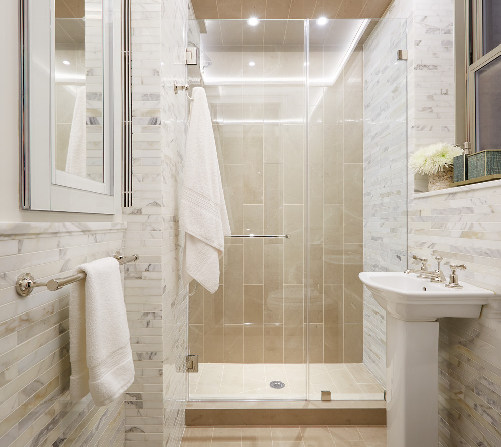 Klassisk inredning av ett litet badrum med dusch, med ett piedestal handfat, en dusch i en alkov, vit kakel, vita väggar, stenkakel och klinkergolv i keramik