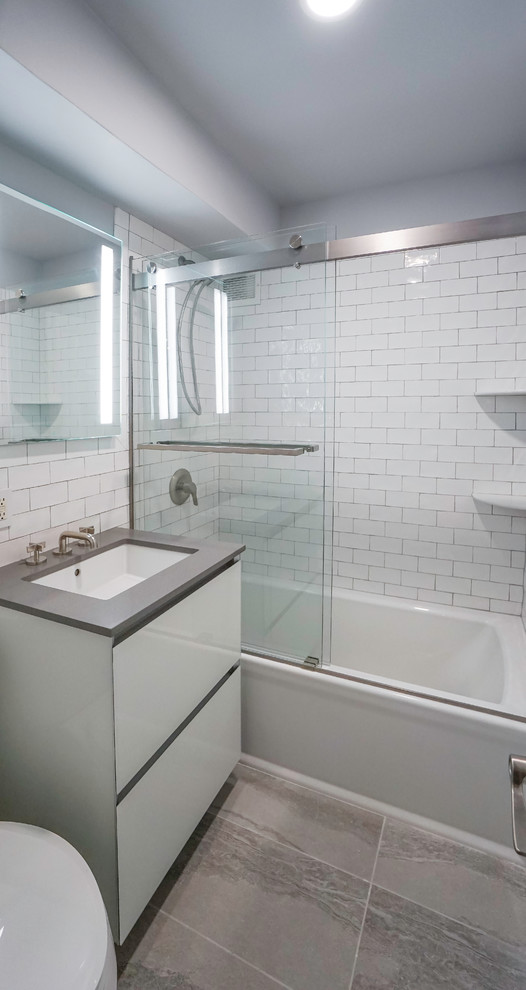 Пример оригинального дизайна: маленькая ванная комната в стиле модернизм с накладной ванной, душем над ванной, белой плиткой, керамической плиткой, серыми стенами, полом из керамической плитки, врезной раковиной, серым полом и душем с раздвижными дверями для на участке и в саду