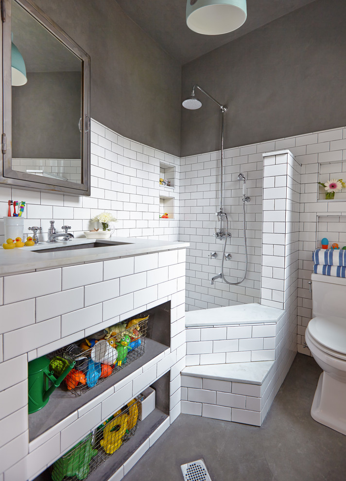 Modelo de cuarto de baño infantil actual con lavabo bajoencimera, ducha esquinera, baldosas y/o azulejos blancos, paredes grises y hornacina