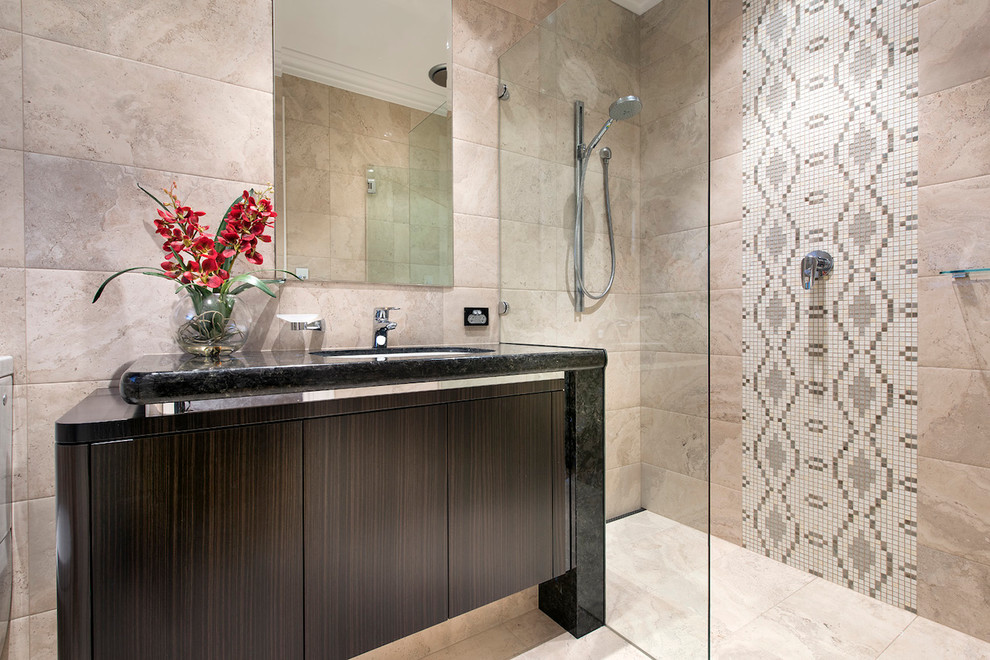 Cette photo montre une salle de bain méditerranéenne en bois foncé avec un lavabo encastré, un placard à porte plane, une douche à l'italienne, un carrelage beige et un mur beige.