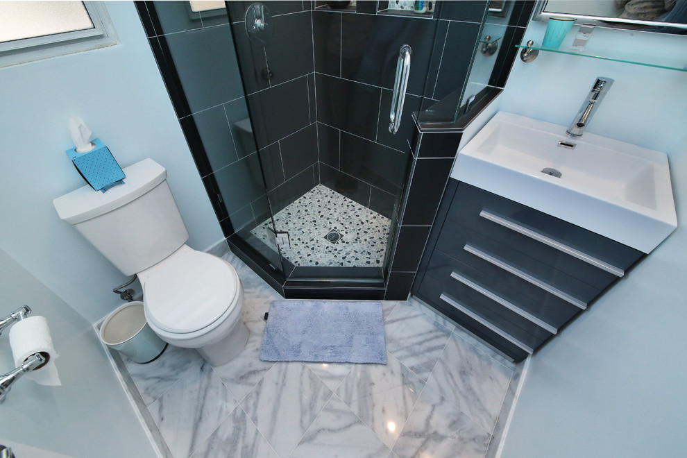 Modern inredning av ett litet en-suite badrum, med ett konsol handfat, luckor med infälld panel, grå skåp, bänkskiva i akrylsten, en hörndusch, en toalettstol med separat cisternkåpa, grå kakel, porslinskakel, blå väggar och marmorgolv