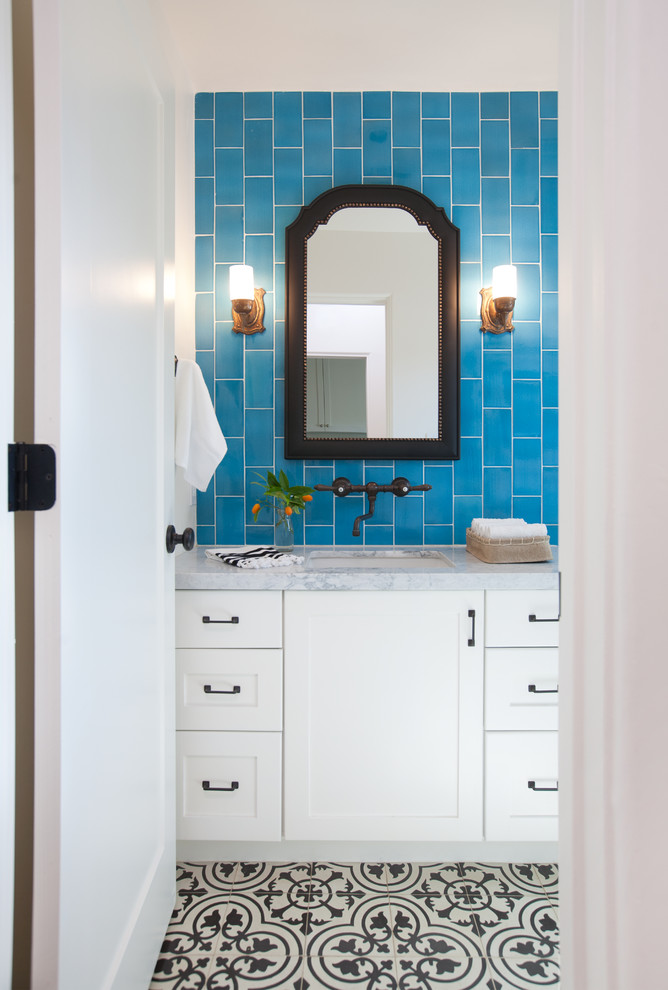 Foto di una stanza da bagno mediterranea con ante in stile shaker, ante bianche, piastrelle nere, piastrelle diamantate, pareti blu, lavabo sottopiano, top in marmo, pavimento in cementine e pavimento multicolore