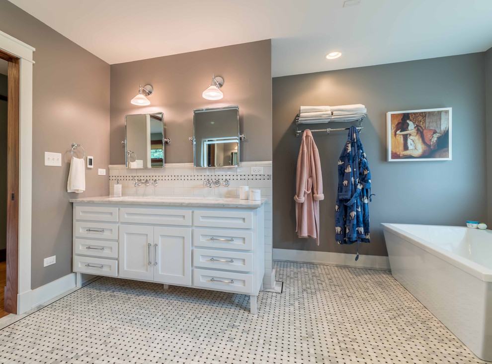 This is an example of a medium sized classic grey and white ensuite bathroom in Chicago with shaker cabinets, white cabinets, a freestanding bath, a two-piece toilet, black and white tiles, metro tiles, grey walls, marble flooring, a submerged sink, marble worktops, white floors, a hinged door, white worktops, an alcove shower, a shower bench, double sinks, a freestanding vanity unit, a wallpapered ceiling and wallpapered walls.