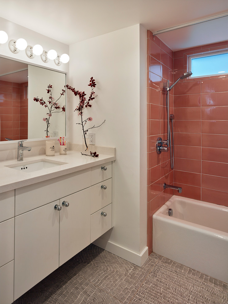 На фото: маленькая детская ванная комната в современном стиле с плоскими фасадами, белыми фасадами, ванной в нише, душем над ванной, унитазом-моноблоком, розовой плиткой, керамической плиткой, белыми стенами, полом из керамогранита, врезной раковиной, столешницей из искусственного кварца, разноцветным полом и шторкой для ванной для на участке и в саду с