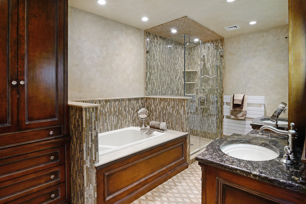 Elegant beige tile and mosaic tile bathroom photo in New York with an undermount sink, recessed-panel cabinets, medium tone wood cabinets, granite countertops and a two-piece toilet