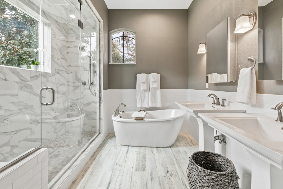 Imagen de cuarto de baño principal, doble y de pie clásico renovado con bañera exenta, sanitario de una pieza, baldosas y/o azulejos blancos, paredes grises, imitación a madera, lavabo con pedestal, suelo gris y banco de ducha