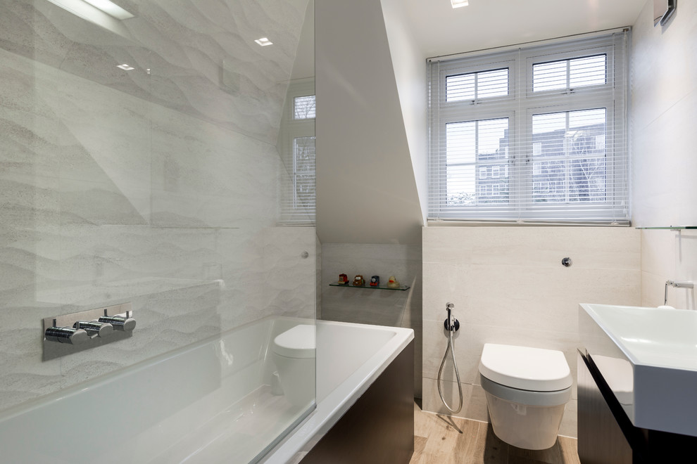 Inspiration for a small contemporary family bathroom in London with flat-panel cabinets, dark wood cabinets, an alcove bath, a walk-in shower, a wall mounted toilet, beige tiles, white tiles, porcelain tiles, white walls, porcelain flooring and a built-in sink.