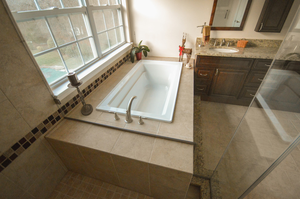 Exemple d'une salle de bain principale chic en bois foncé avec un lavabo encastré, un placard avec porte à panneau encastré, un plan de toilette en granite, une baignoire posée, une douche d'angle, un carrelage beige, un carrelage en pâte de verre, un mur beige et tomettes au sol.