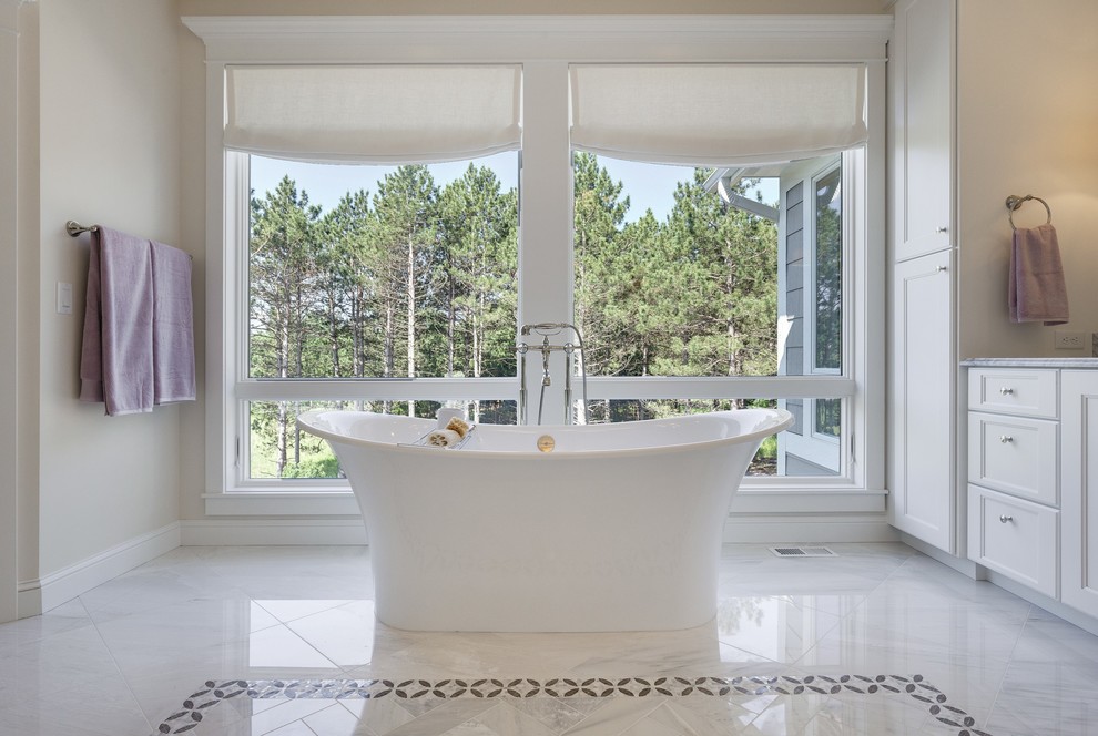 На фото: главная ванная комната среднего размера в классическом стиле с отдельно стоящей ванной, мраморным полом, белым полом, фасадами с утопленной филенкой, белыми фасадами, бежевыми стенами и столешницей из гранита с