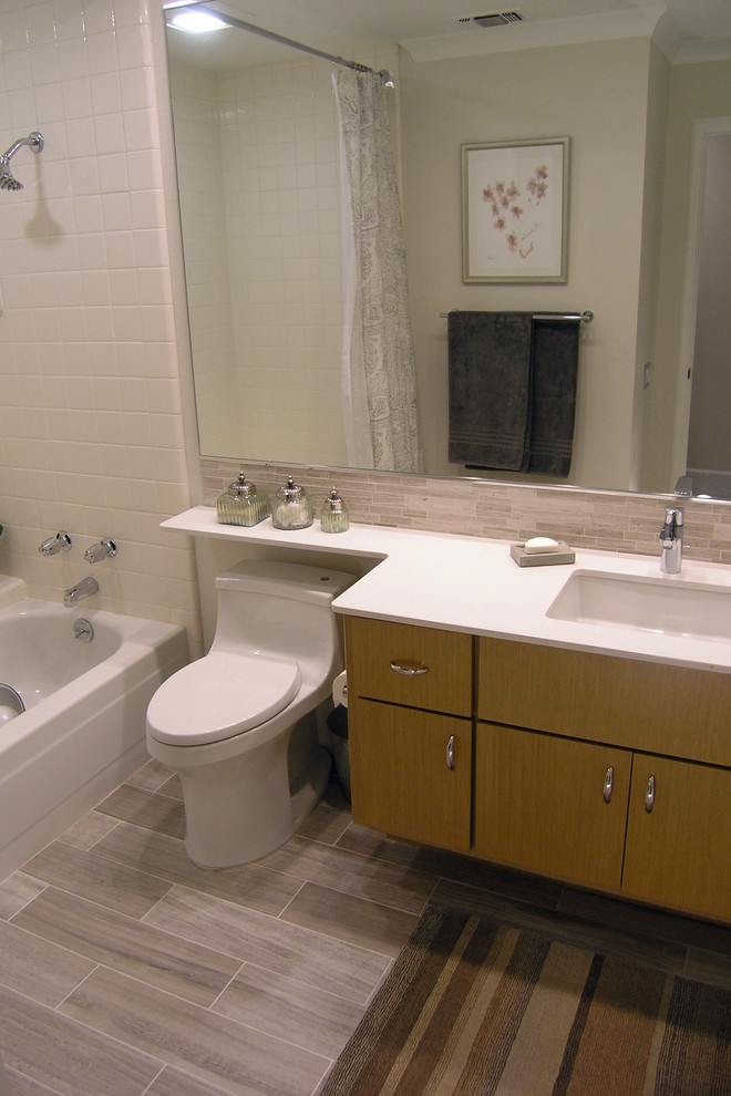 На фото: ванная комната среднего размера в современном стиле с плоскими фасадами, светлыми деревянными фасадами, ванной в нише, душем над ванной, унитазом-моноблоком, серой плиткой, удлиненной плиткой, белыми стенами, полом из керамогранита, врезной раковиной, столешницей из искусственного кварца, коричневым полом и шторкой для ванной с