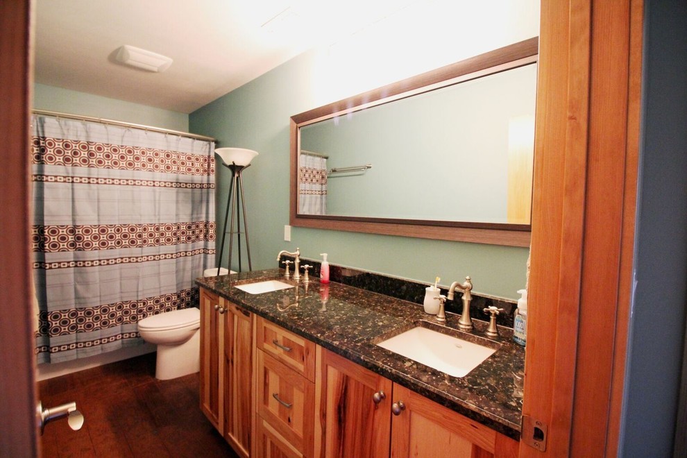 Foto på ett vintage brun badrum, med skåp i shakerstil, skåp i mellenmörkt trä, ett badkar i en alkov, en dusch/badkar-kombination, en toalettstol med separat cisternkåpa, gröna väggar, ett undermonterad handfat, granitbänkskiva, dusch med duschdraperi, betonggolv och brunt golv