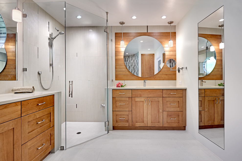Cette image montre une grande salle de bain principale design en bois clair avec un placard à porte shaker, une douche d'angle, un mur beige, un sol en carrelage de porcelaine, un lavabo encastré et un plan de toilette en surface solide.